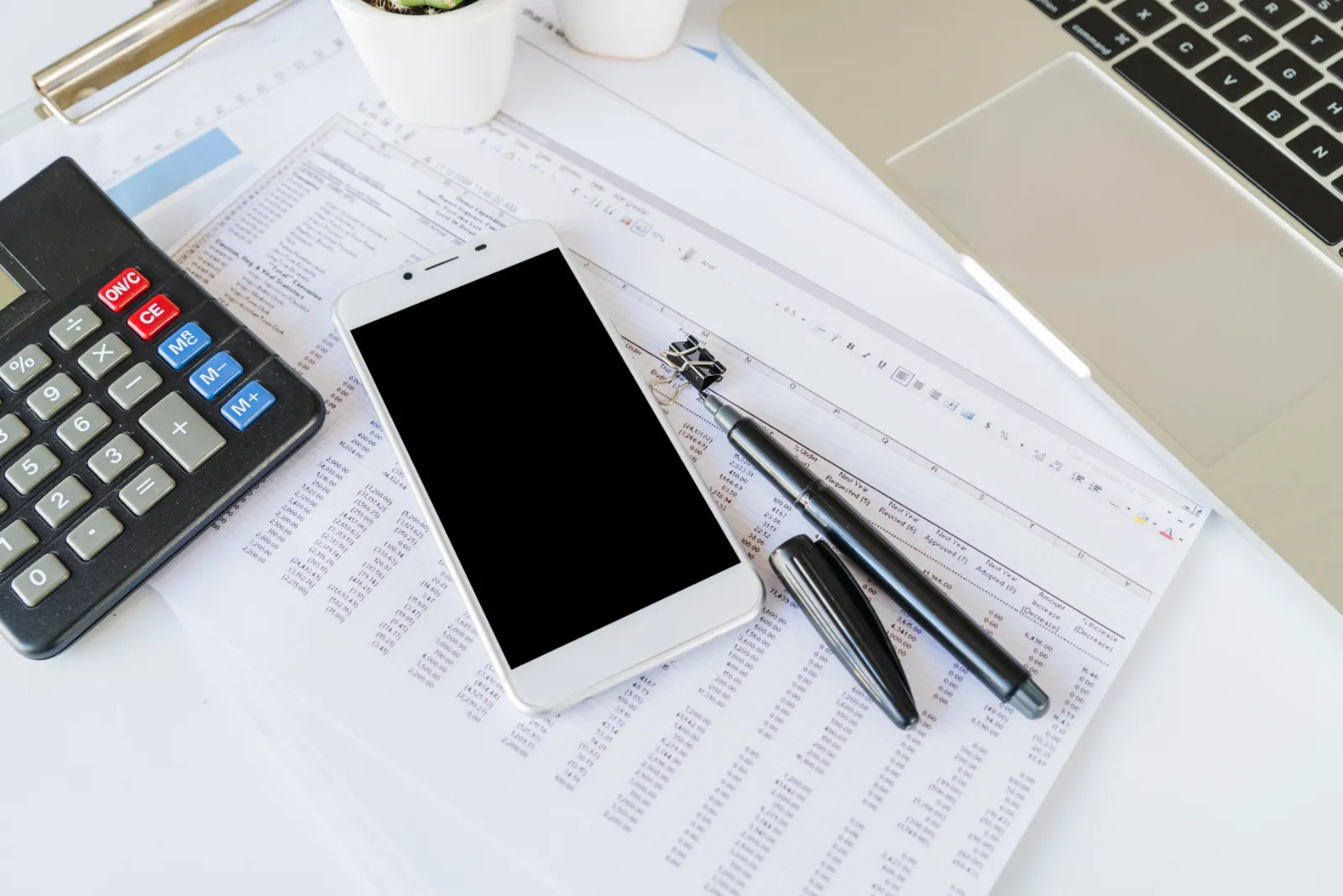 Calcolatrice, smartphone e documenti contabili sulla scrivania