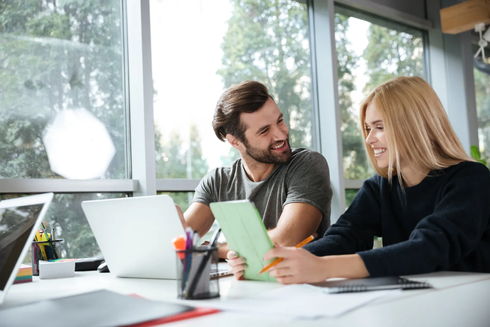 Due giovani consulenti dello studio al lavoro con portatile e documenti